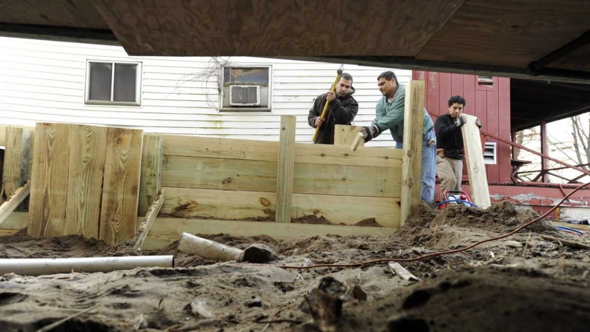 In this Tuesday, Dec. 4, 2012 photo, builders Reginaldo Ferreira, left, Liudmil Petrov, center, and Carlos Martinez of Russe Builders construct a wall to protect a beachfront home in Fairfield, Conn. (AP Photo/Jessica Hill)