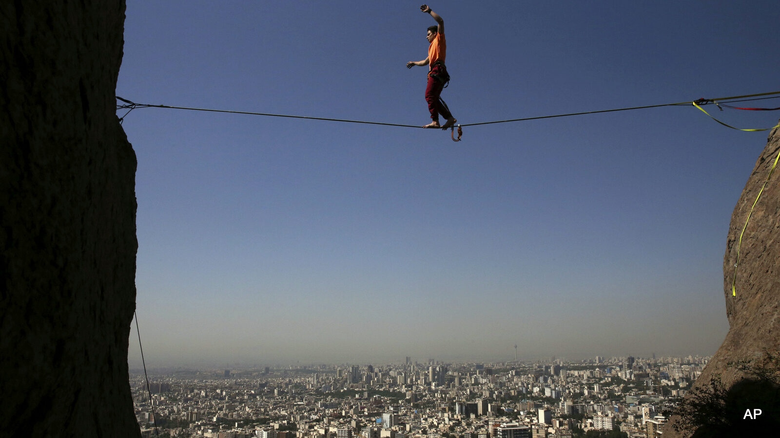 In this picture taken Friday, May 22, 2015, Iranian Hamed Heidari walks across a slackline anchored between two rocks during practice in the mountains overlooking Tehran, Iran. Heidari is one of a growing number of Iranians embracing the extreme sport of slacklining -- a high-wire walk on a flat line of webbing strung between rocks or trees up to 60 meters above the ground.