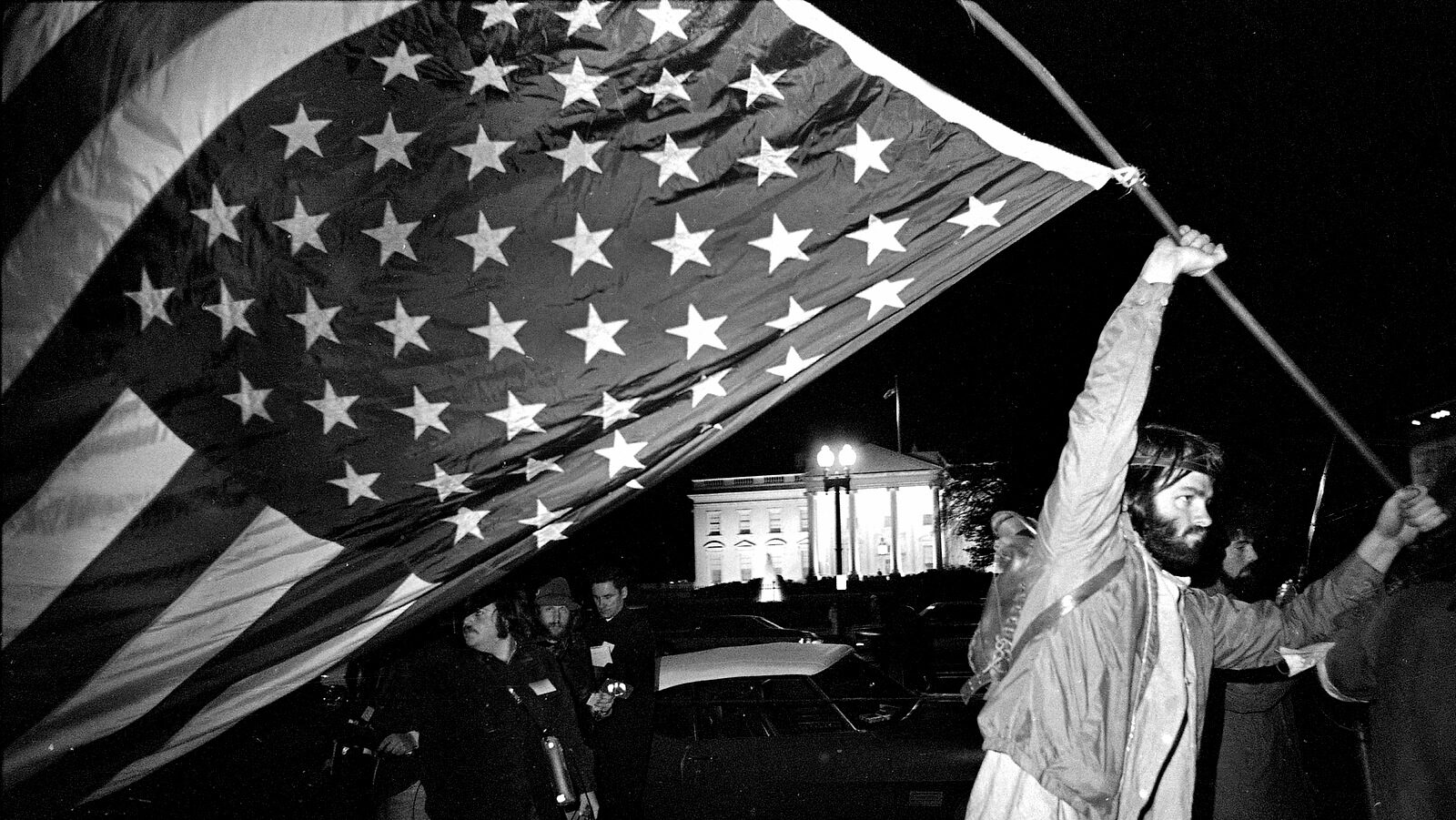 a demonstrator carries an inverted flag, a symbol of distress, as protesters against the Vietnam War march past the White House