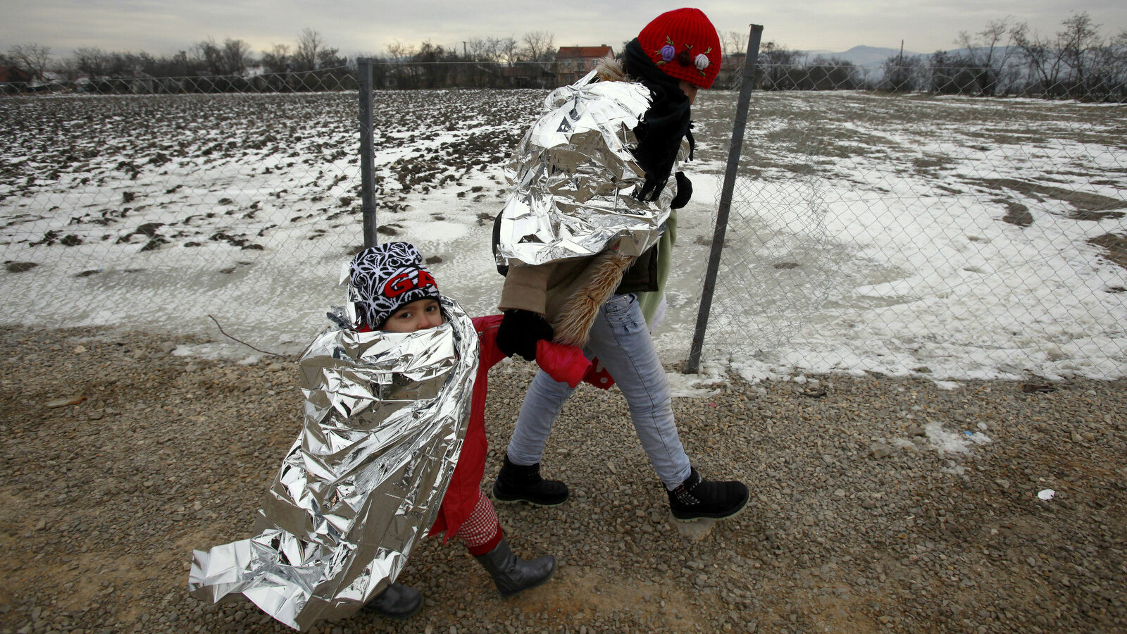 Refugee woman and a child, wrapped in thermal blankets, walk in freezing weather towards the border with Serbia from the transit center for refugees near northern Macedonian village of Tabanovce on their journey toward Western Europe Sunday, Jan. 24, 2016. Macedonia, Serbia and Croatia, the countries on the so-called Balkan migrant corridor that starts in Greece, are only letting in people whose stated final destination is Germany or Austria. (AP Photo/Boris Grdanoski)