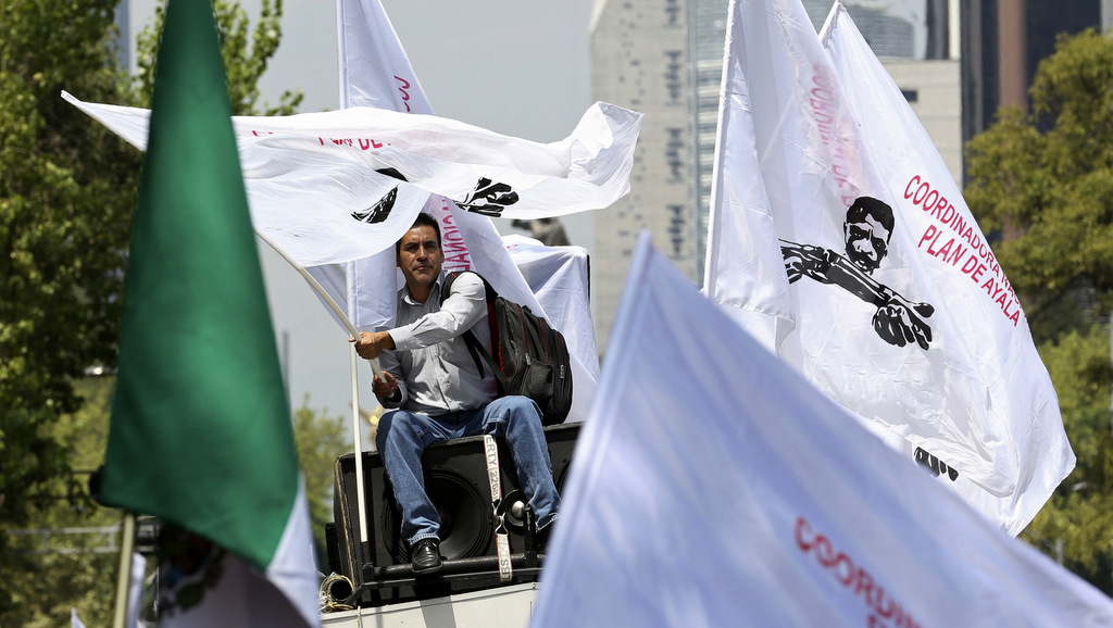 A man on the top of a van waves a flag during a farmers' protest in Mexico City, Monday, Aug. 7, 2017. Farmers marched to the Interior Ministry demanding the agricultural sector be removed from the North American Free Trade Agreement as the Trump administration prepares to renegotiate NAFTA with Mexico and Canada. (AP/Gustavo Martinez Contreras)