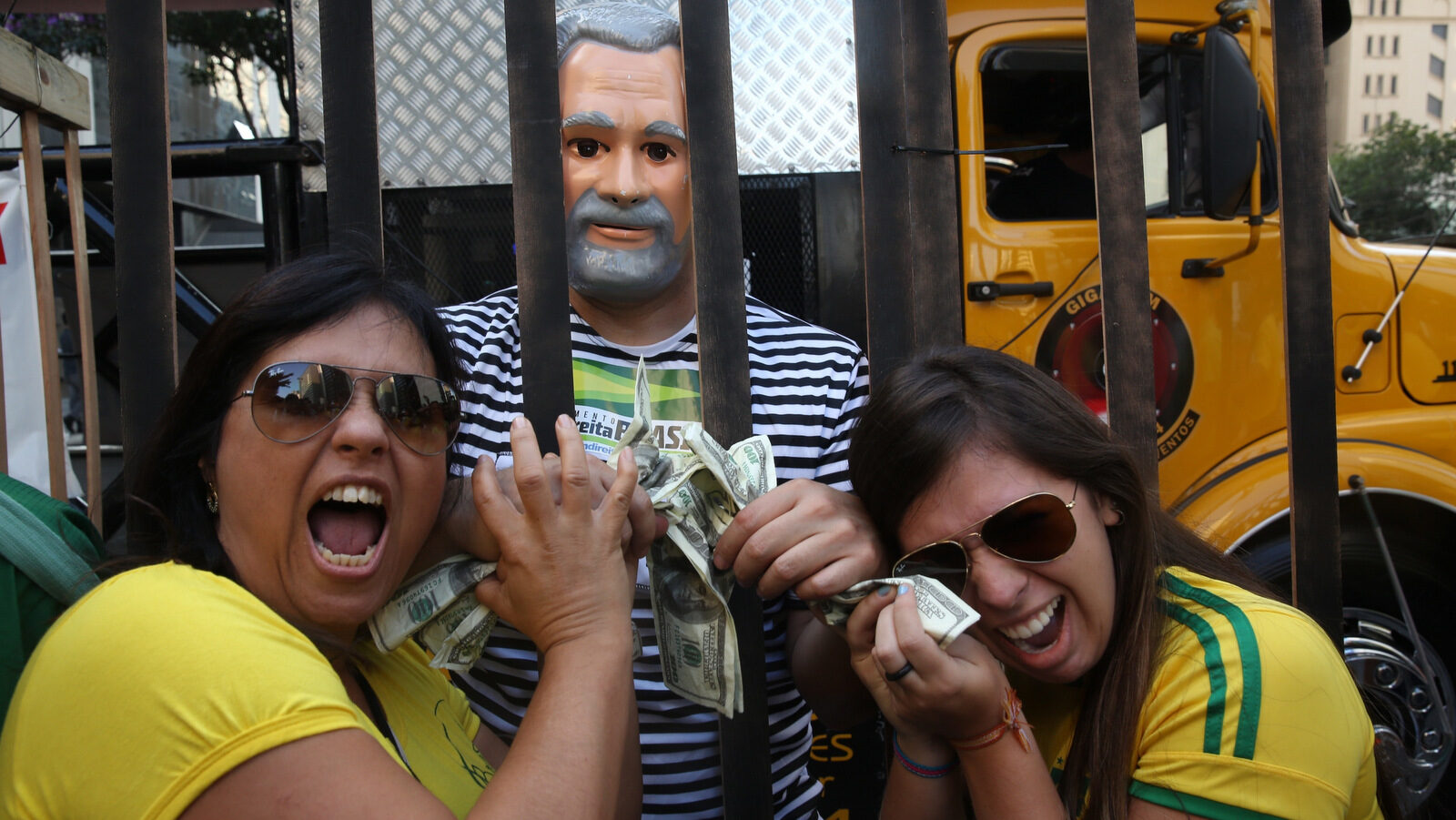 Demonstrators, one dressed as a prisoner and wearing a mask with the likeness of Brazil's former President Luiz Inacio Lula da Silva, joke with fake money from a mock jail during a protest demanding the impeachment of Brazil's President Dilma Rousseff in Sao Paulo, Brazil. Half of Brazilians want former President Luiz Inacio Lula da Silva to win 2018's election and return to the office he occupied between 2003 and 2010. The other half wants him in prison. (AP/Andre Penner)