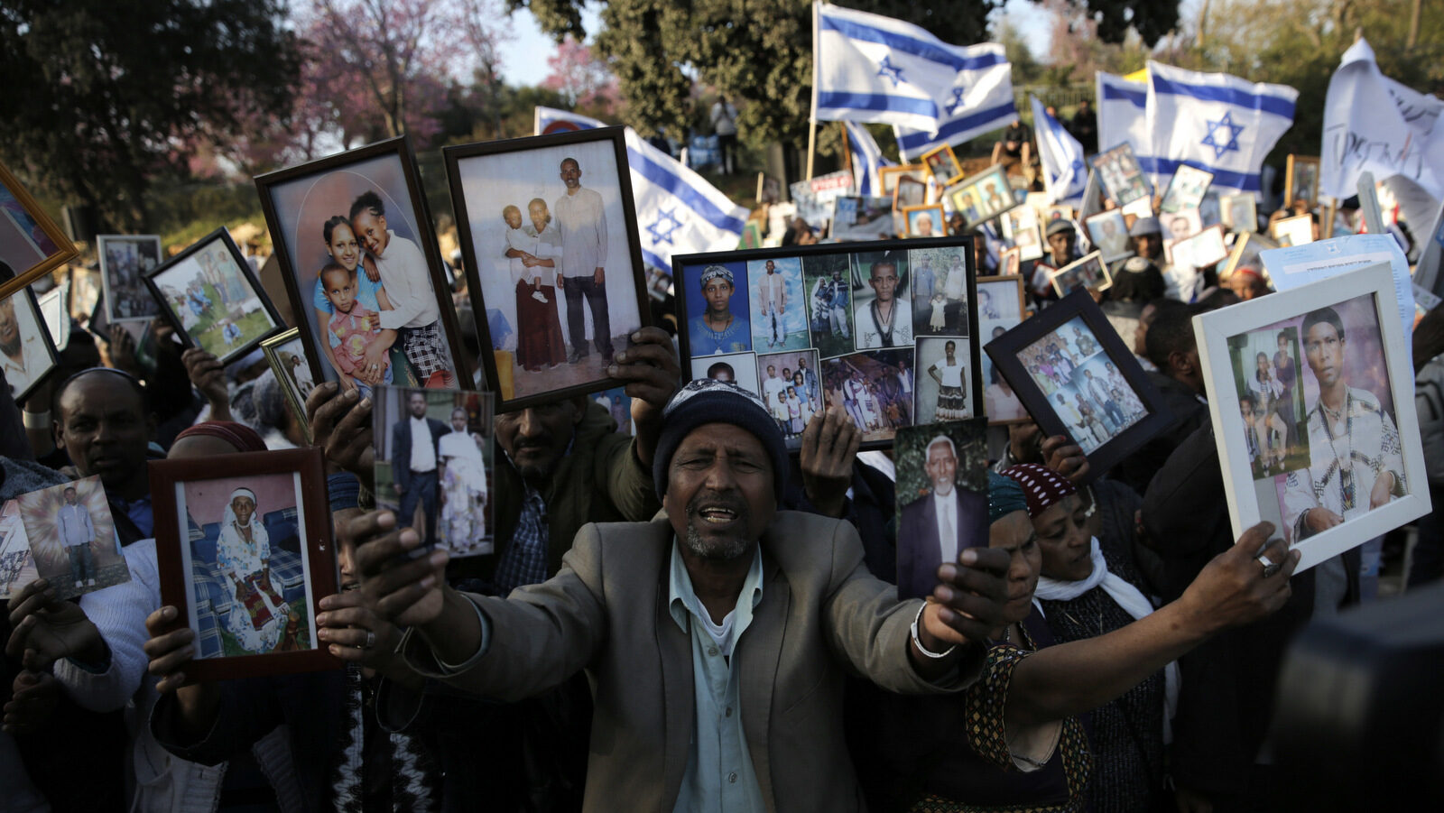 Ethiopian Israelis hold pictures of relatives as they protest in front of the Knesset, Israel's parliament in Jerusalem, March 12, 2018. Hundreds of Ethiopian immigrants are protesting outside Israel's parliament, demanding the government fulfill a pledge to bring some 8,000 of their countrymen remaining in Ethiopia to Israel. (AP/Sebastian Scheiner)