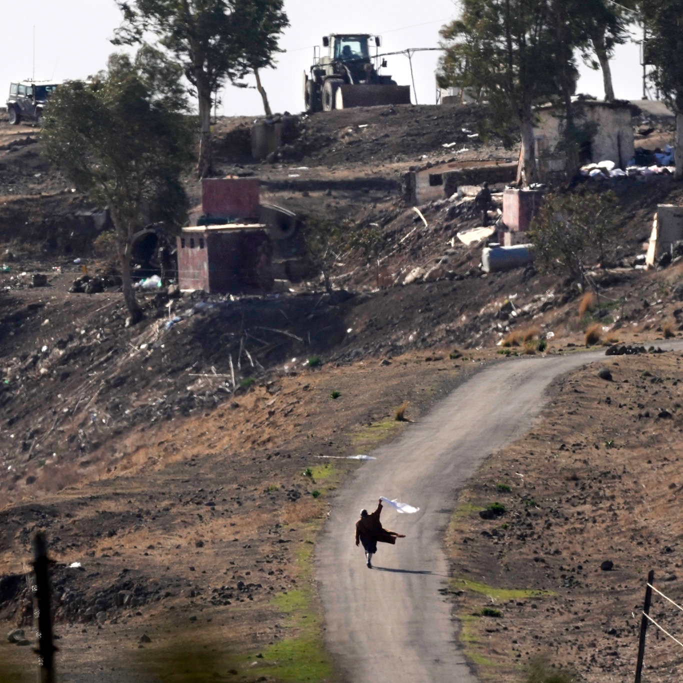 A Syrian man waves a white flag as he approaches Israeli soldiers in Maariyah, Syria, Dec. 19, 2024. Hussein Malla | AP